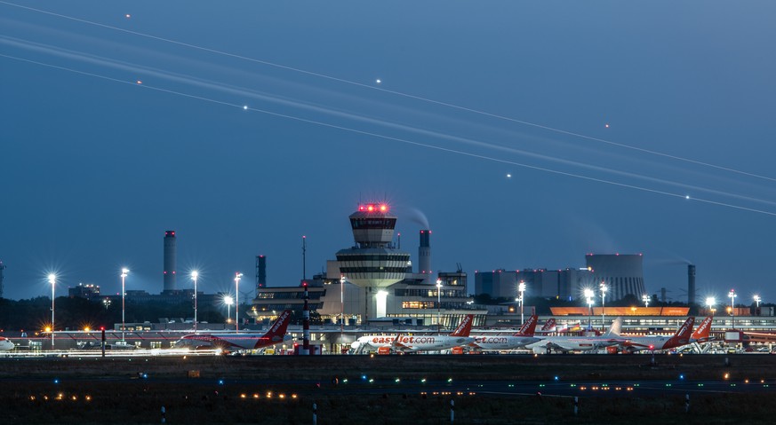 18.07.2018, Berlin: Nur als Lichtstreifen ist am Abend ein sich im Anflug befindendes Flugzeug am Flughafen Tegel zu erkennen. Foto: Paul Zinken/dpa +++ dpa-Bildfunk +++