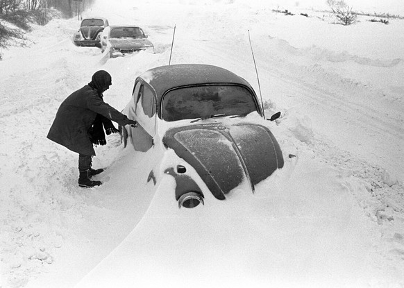 ARCHIV - 31.12.1978, Niedersachsen, Cuxhaven: Ein Autofahrer steht neben seinem am Stra�enrand im Schnee stecken gebliebenen VW-K�fer, aufgenommen bei Cuxhaven am 31.12.1978. Der Temperatursturz vom 2 ...