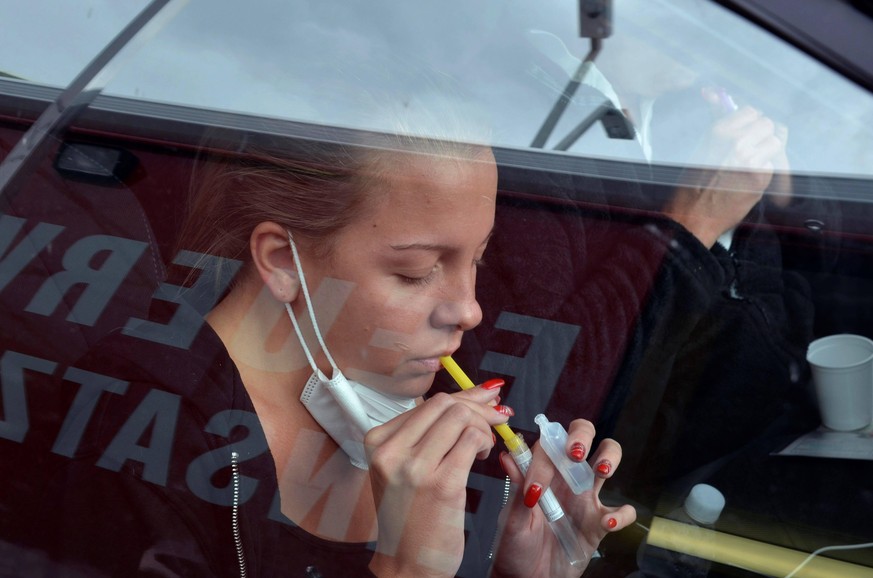 A young woman makes a gargle test from her car to detect the Covid-19 in the test lane set up next to the Ernst Happel soccer stadium in Vienna Austria, 09 October 2020. Citizens can come with their r ...