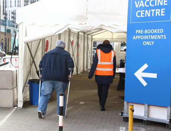 January 21, 2021, London, United Kingdom: An elderly man on crutches walks into the vaccination centre.A steady stream of elderly people with pre-booked appointments at the new Covid-19 Vaccination hu ...