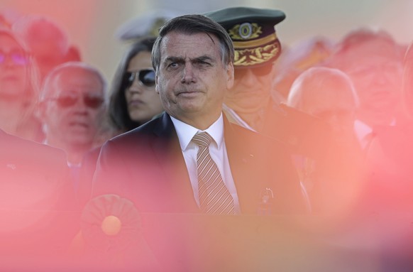 With the red plumes of the helmets of the honor guard in the foreground, wldBrazils President Jair Bolsonaro attends during a military ceremony for the Day of the Soldier, at Army Headquarters in Bras ...