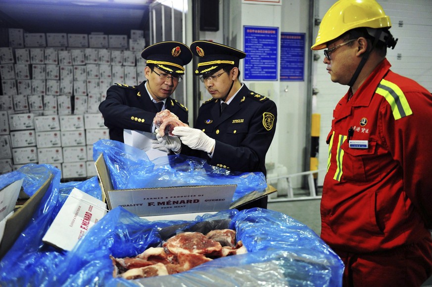 In this April 13, 2017, photo, a warehouse worker watches as government inspectors check imported frozen pork in Qingdao in eastern China&#039;s Shandong province. China announced a list of U.S. goods ...