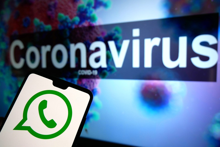 Coronavirus Stock The Whatsapp logo seen displayed on a mobile phone with an illustrative model of the Coronavirus displayed on a monitor in the background. Photo credit should read: James Warwick/EMP ...