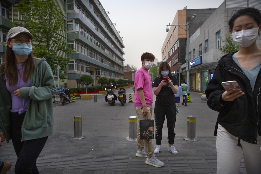 24.04.2020, China, Peking: Kunden tragen Mundschutz bei ihrem Besuch einer pekinger Freilufteinkaufsmeile. Foto: Mark Schiefelbein/AP/dpa +++ dpa-Bildfunk +++