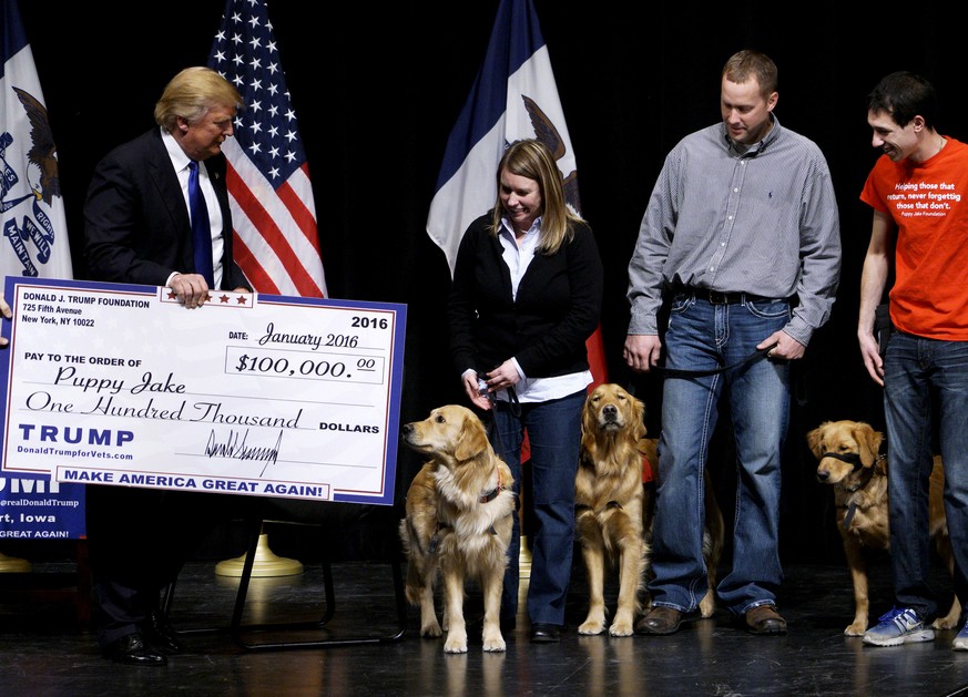 FILE PHOTO: U.S. Republican presidential candidate Donald Trump presents a mock check from the Trump Foundation representing $100,000 to members of the Puppy Jake Foundation, which provides military v ...