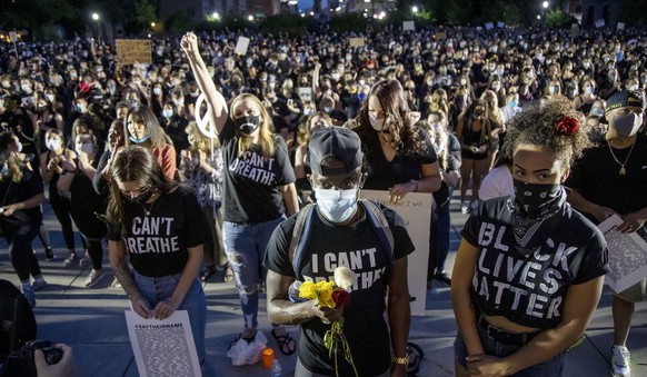 In this Tuesday, June 2, 2020 photo, Dele Ogunrinola, center, and Ariana Jenks, right, both of Boise, join thousands at the Idaho Statehouse in Boise for a vigil in remembrance of George Floyd, a blac ...