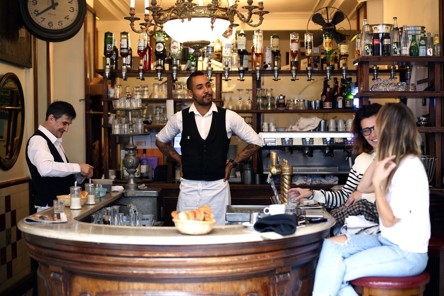 Waiters Jean Baptiste Magnique, center, and Didier Hubert talks with customer of the cafe &quot;Au petit Fer a Cheval&quot; (The small horseshoe), in the historical Marais district of Paris, Thursday, ...