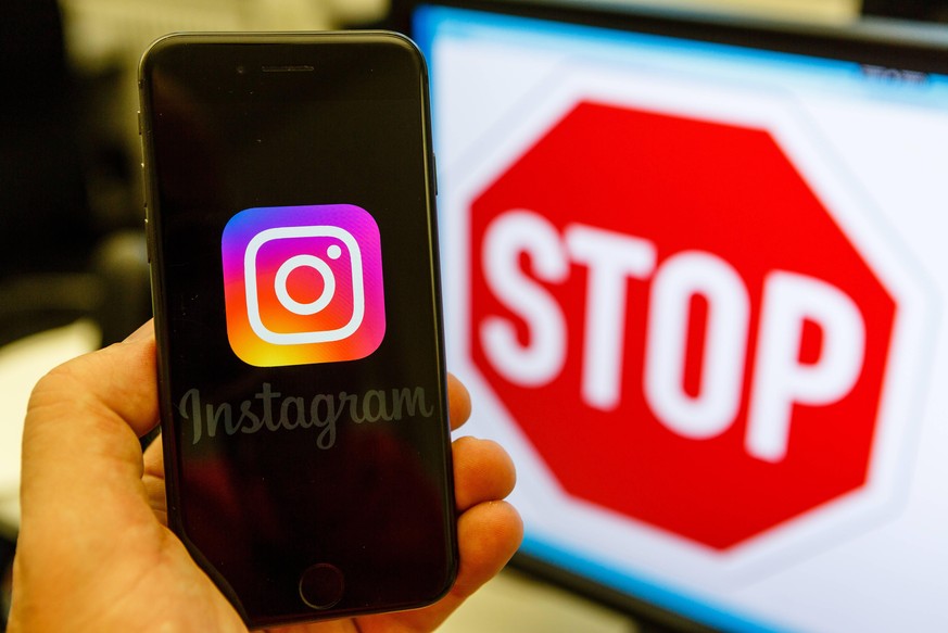 Symbolfoto Instagram, Instagram Logo auf einem iPhone - im Hintergrund auf einem Computer Bildschirm ein Stop-Schild *** Symbol photo Instagram Instagram logo on an iPhone in the background on a compu ...