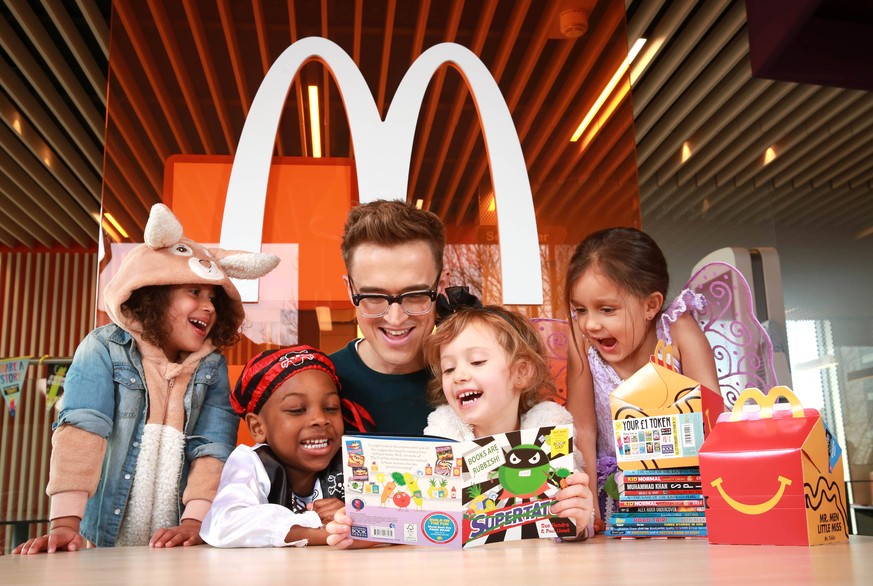 World Book Day EDITORIAL USE ONLY Children s author and musician Tom Fletcher reads to left to right four year olds Pearl Prasad, Zane-Ellis Yeboah, Maisie Patey, and five year old Alexandra Ancharaz, ...