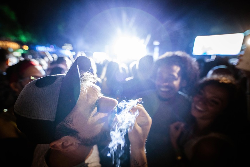 Young man smoking weed during music concert by night.