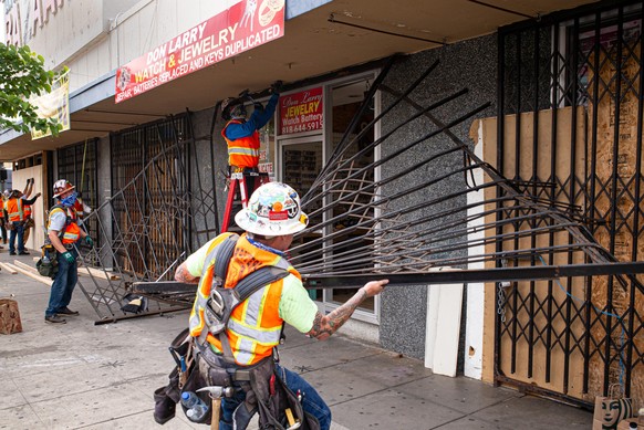 02.06.2020, USA, Van Nuys: Arbeiter entfernen ein beschädigtes Gitter vor der Fassade eines Juweliers, das im Zuge von Plünderungen bei einem Protest beschädigt wurde. Der gewaltsame Tod des Afroameri ...