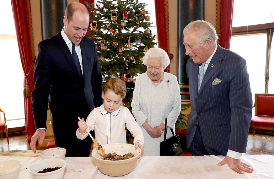 An undated photograph released on December 21, 2019 by Buckingham Palace shows Britain&#039;s Queen Elizabeth, Prince Charles, Prince William, and Prince George preparing special Christmas puddings in ...