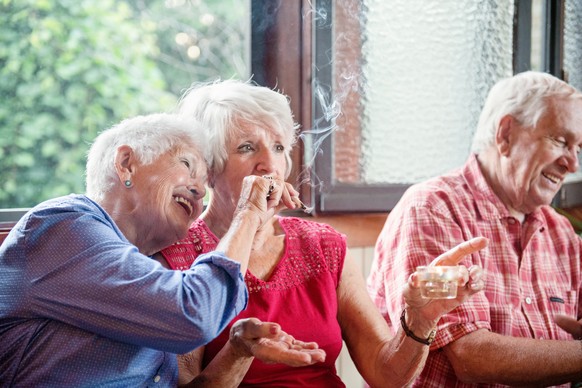 Old Two senior girlfriends 83 years old smoke medicinal marijuana together. They have gray hair. One of them shows the other how to do. The old lady is surprised and they are having fun. They have hai ...