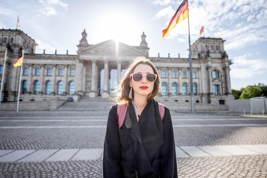 Woman standing in front of the famous Bundestag building in Berlin during the sunrise