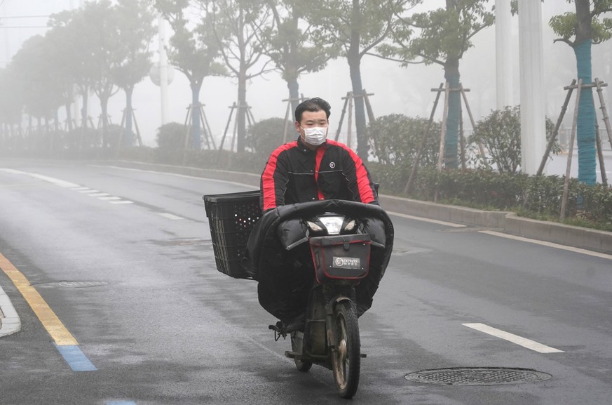 200223 -- WUHAN, Feb. 23, 2020 -- A delivery man is seen working amid fog in Wuhan, central China s Hubei Province, Feb. 22, 2020. Xinhua Headlines: Under the masked sky: Wuhan makes lockdown sacrific ...
