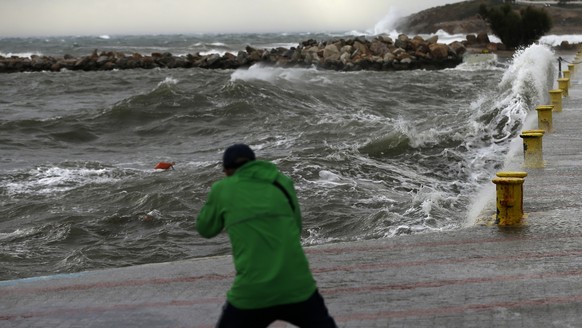A man takes a photograph during bad weather at the port of Rafina, east of Athens, on Thursday, Sept. 27, 2018. Severe weather warnings remain in effect around Greece, halting ferry services and promp ...