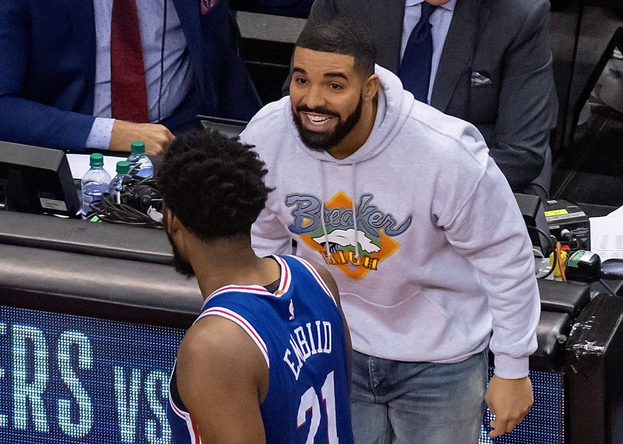 Canadian hip hop musician Drake (rear) smiles at Philadelphia 76ers center Joel Embiid as he leaves the court after the Toronto Raptors defeated the Philadelphia 76ers 125-89 in Game 5 in their NBA Ba ...
