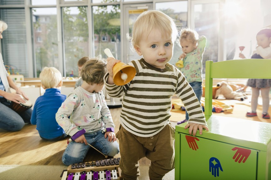 Toddler ringing a bell in music room of a kindergarten model released Symbolfoto property released PUBLICATIONxINxGERxSUIxAUTxHUNxONLY MFF04080