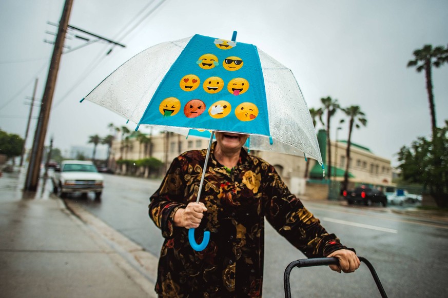 May 16, 2019 - San Bernardino, California, U.S. - Kathy Sorthon smiles as she walks under her emoji umbrella along the 700 block of D st. as rain falls in San Bernardino on Thursday, May 16, 2019. San ...