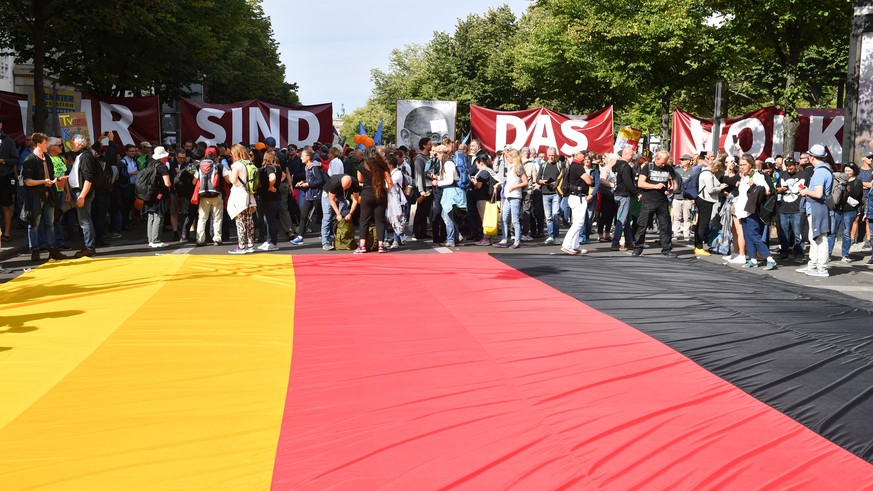 29.08.2020, Berlin: Teilnehmer sammeln sich hinter einer großen deutschen Fahne auf der Straße zu einer Demonstration gegen die Corona-Maßnahmen. Foto: Bernd Von Jutrczenka/dpa +++ dpa-Bildfunk +++