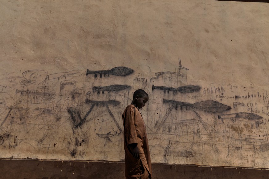Picture nominated for World Press Photo of the Year at the World Press photo contest shows: An orphaned boy walks past a wall with drawings depicting rocket-propelled grenade launchers, in Bol, Chad O ...