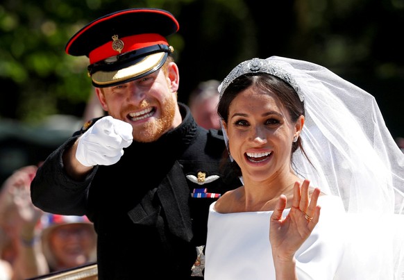 FILE PHOTO: Britain&#039;s Prince Harry gestures next to his wife Meghan as they ride a horse-drawn carriage after their wedding ceremony at St George&#039;s Chapel in Windsor Castle in Windsor, Brita ...