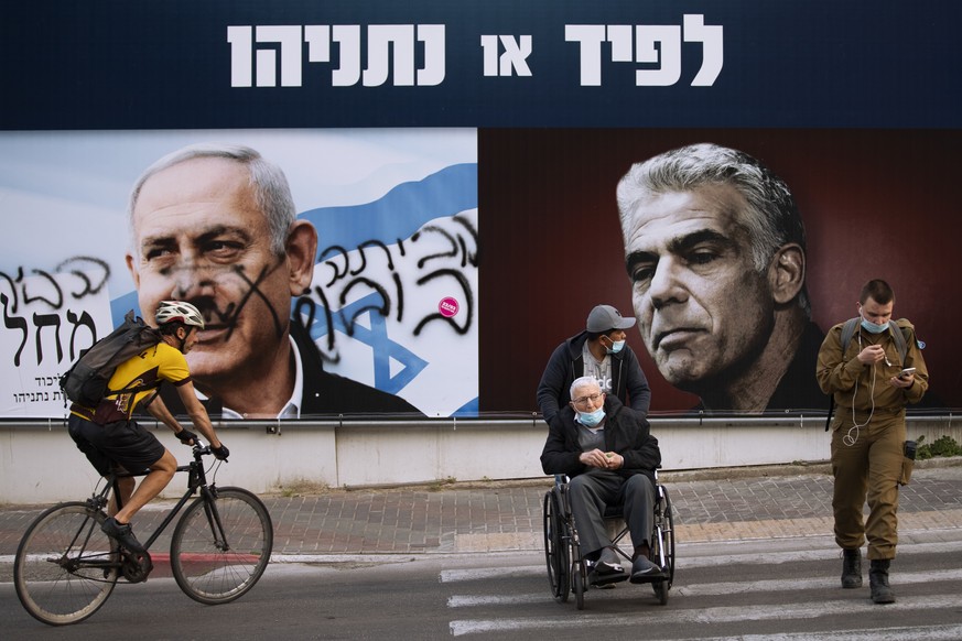 An election campaign billboard for the Likud party that shows a portrait of its leader Prime Minister Benjamin Netanyahu, left, and opposition party leader Yair Lapid, is defaced with Hebrew that read ...