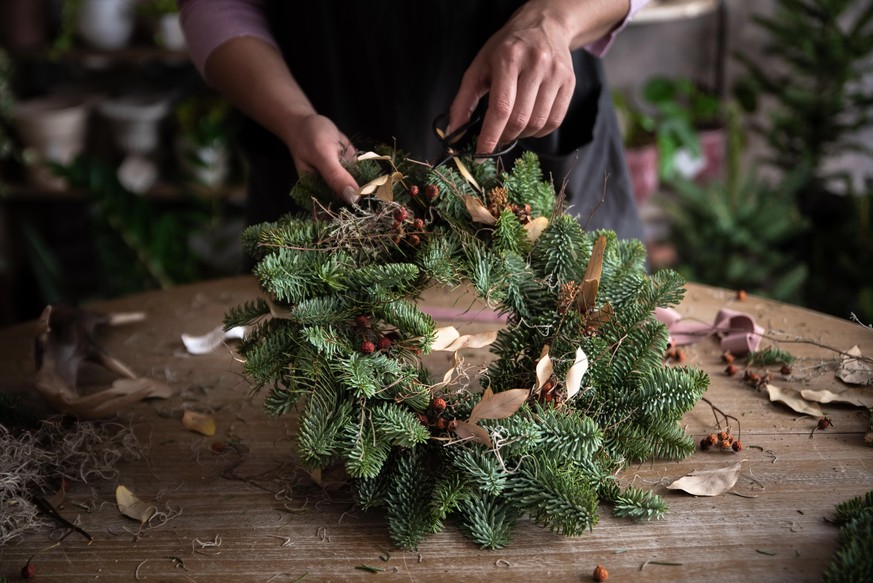 Woman making Christmas wreath of spruce, step by step. Concept of florist&#039;s work before the Christmas holidays.