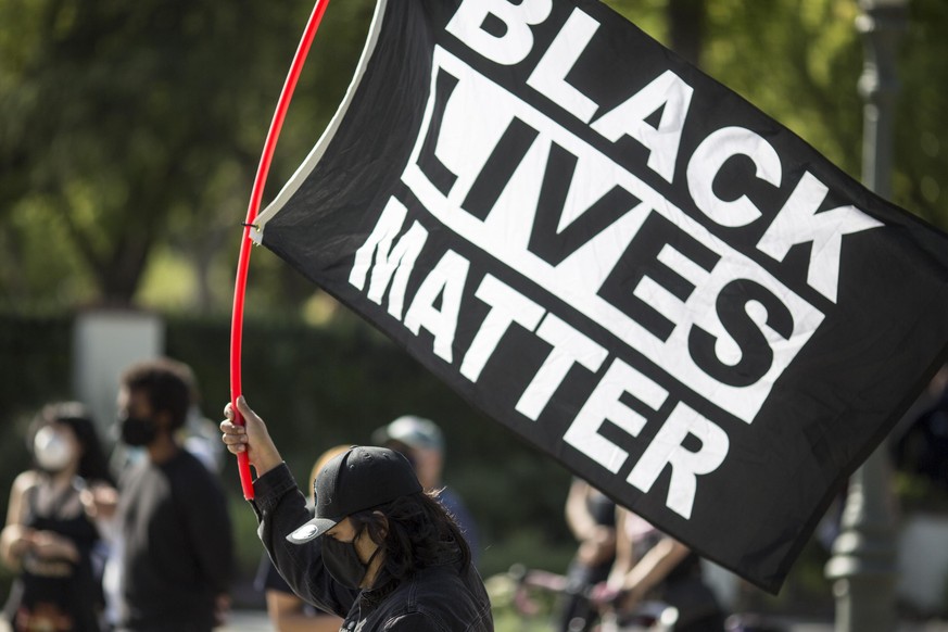 A man holding a BLACK LIVES MATTER flag outside Los Angeles Mayor Garcetti&#039;s house after a guilty verdict was announced at the trial of former Minneapolis police Officer Derek Chauvin for the 202 ...