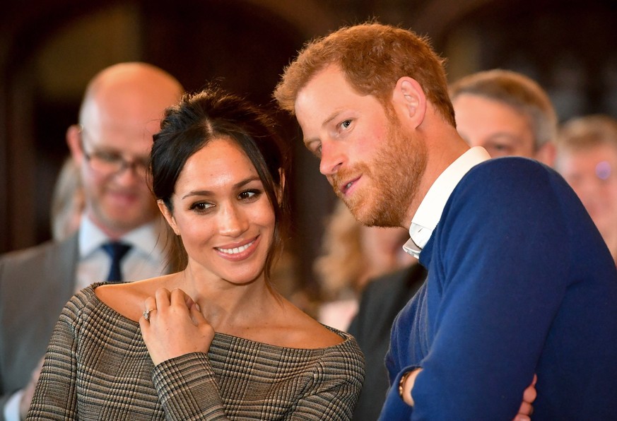 CARDIFF, WALES - JANUARY 18: Prince Harry whispers to Meghan Markle as they watch a dance performance by Jukebox Collective in the banqueting hall during a visit to Cardiff Castle on January 18, 2018  ...