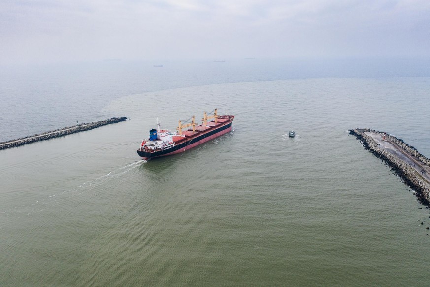 The pilot ship accompanies the cargo vessel at the exit from the shipping channel. Aerial drone shot taken in Kaliningrad region, Russia.