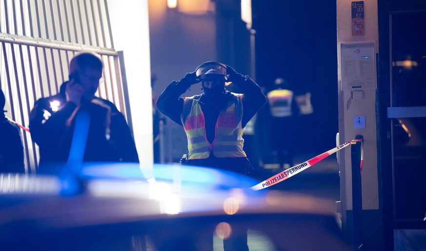 26.12.2020, Berlin: Polizeibeamte stehen vor einer Toreinfahrt zu einem Geb