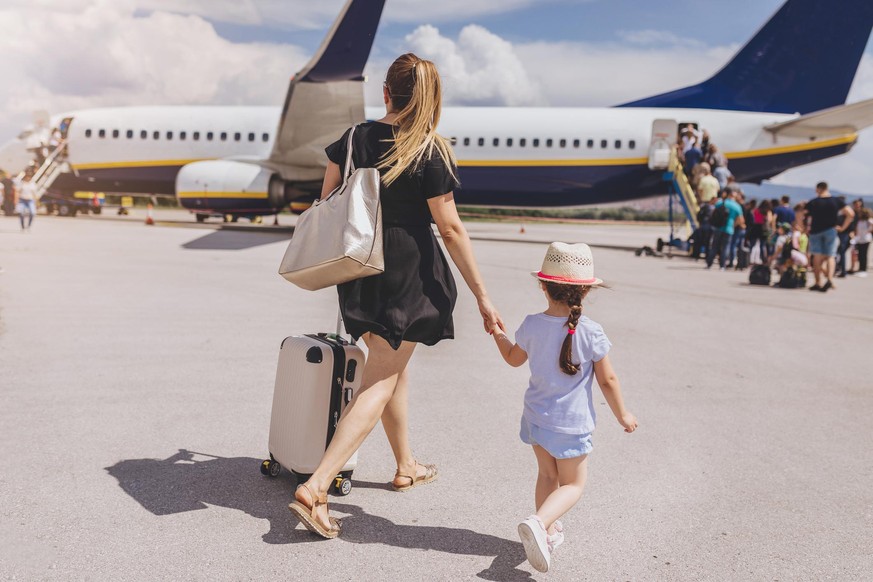 Young mother and her beautiful daughter boarding a plane.