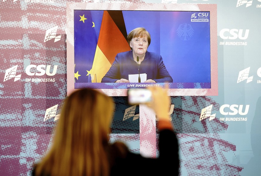 German Chancellor Angela Merkel is seen on a screen, making a statement on the events in Washington with the storming of the Capitol by Trump supporters at the beginning of the digital press conferenc ...